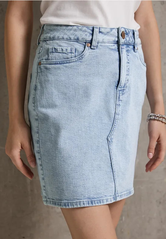 Frau trägt einen hellblauen Jeansrock und ein weißes T-Shirt.